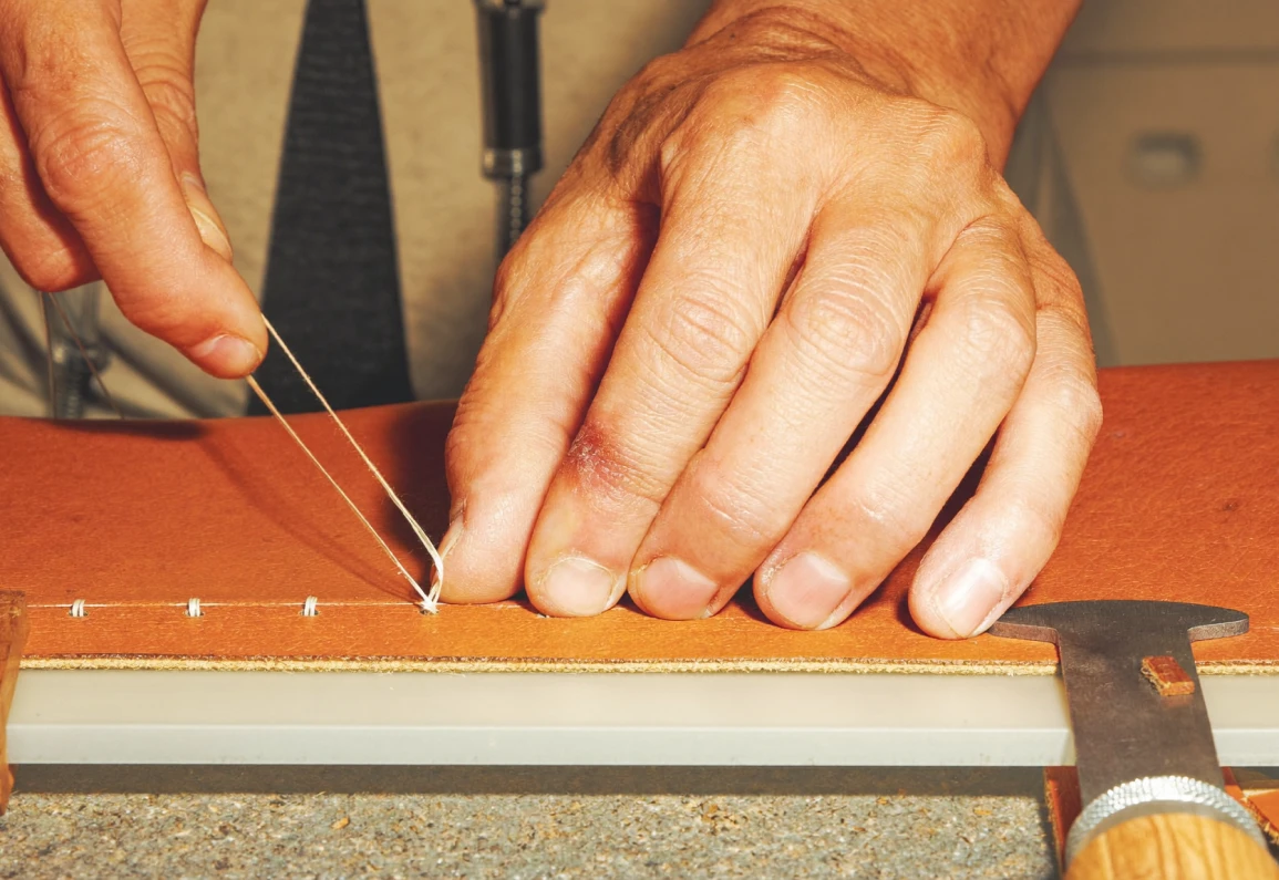 Hands stretching and inspecting richly textured orange leather